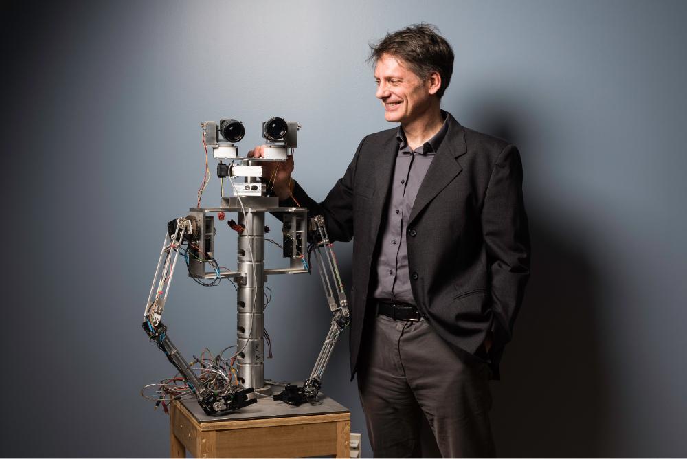 教师 robotics researcher standing next to robot head and upper torso at University of Rochester